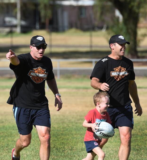 Former Manly Sea Eagle great Steve Menzies points out a way to go for this young Werris Creek junior as Freddy Fittler laughs on on Monday. The Hogs For Homeless were in Inverell yesterday and are off to Lismore and Lennox Head today. Photo: Gareth Gardner  230215GGE06