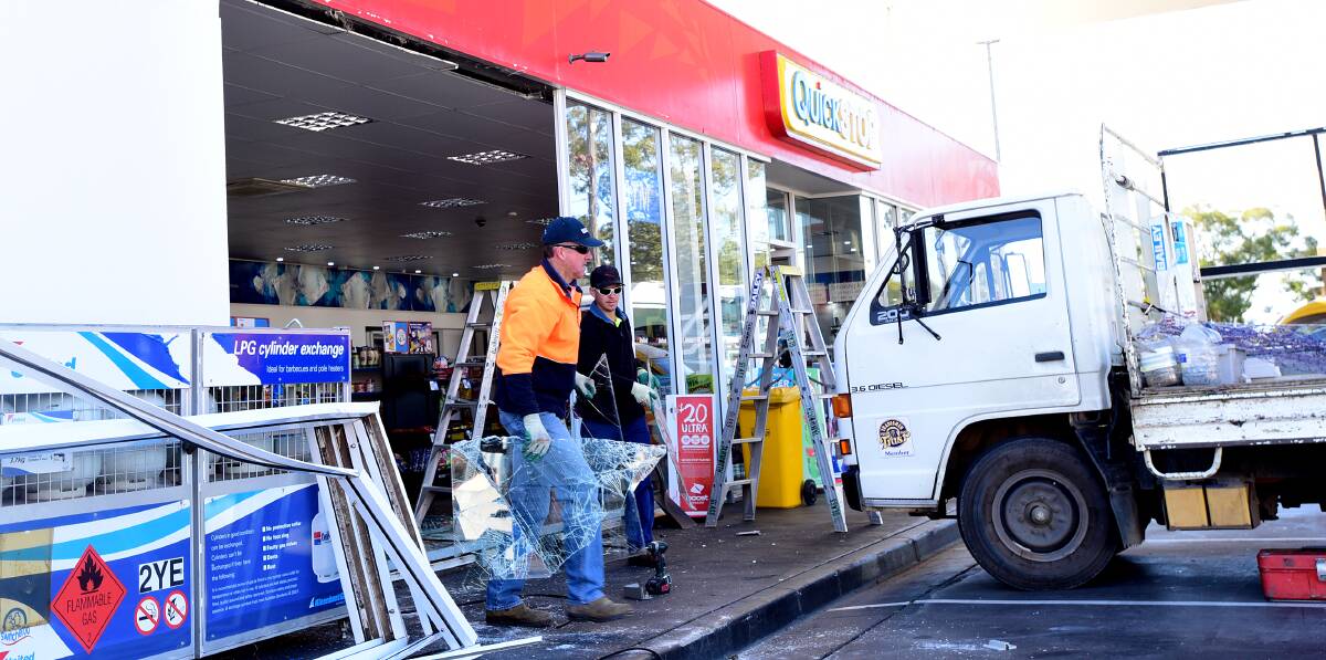 COSTLY DAMAGE: Tradesmen were called in to the United Service Station to repair the front windows yesterday morning. Photo: Gareth Gardner 070715GGA02
