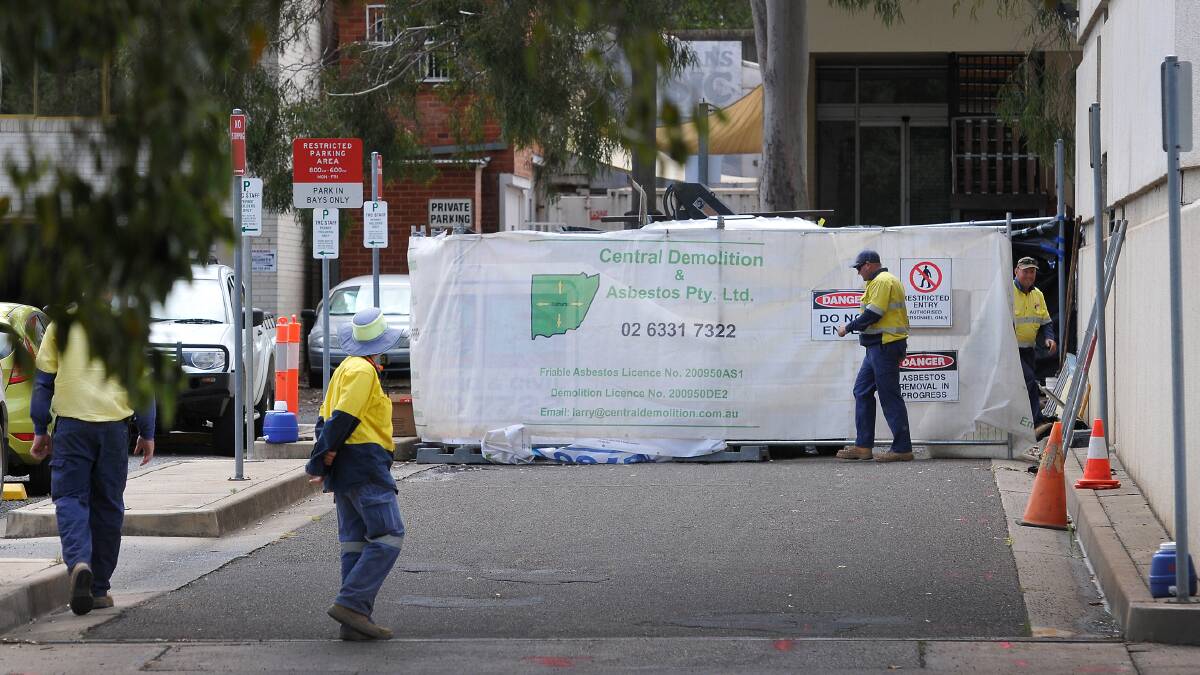 SAFETY FIRST: Essential Energy contractors carry out work on Ray Walsh House in Tamworth after asbestos was discovered in a basement area. Photo: Gareth Gardner 061114GGA01