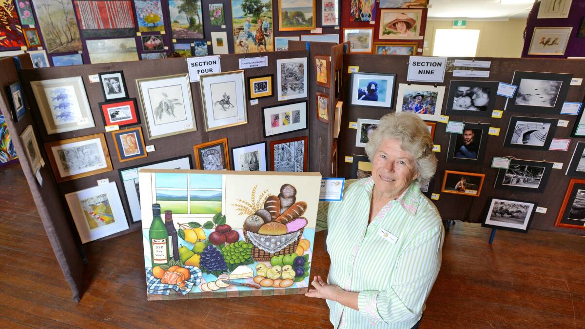 OPEN FOR INSPECTION: Bendemeer’s Colours of Autumn Art and Craft Show committee treasurer Nicole McFarlane, with Taste of Tamworth section Diane Betts’s winning painting, featured at the Bendemeer Community Hall. Photo: Barry Smith 140415BSA10