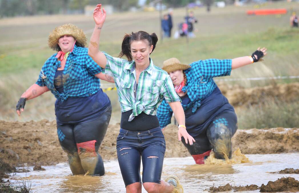 CAREFUL AS SHE GOES: Stacey Kiddle, front, uses her arms to maintain balance while negotiating some of the 1.5 kilometres of mud in the Suck It Up Buttercup Mud Race on Saturday. Photo: Gareth Gardner 030514GGA29
