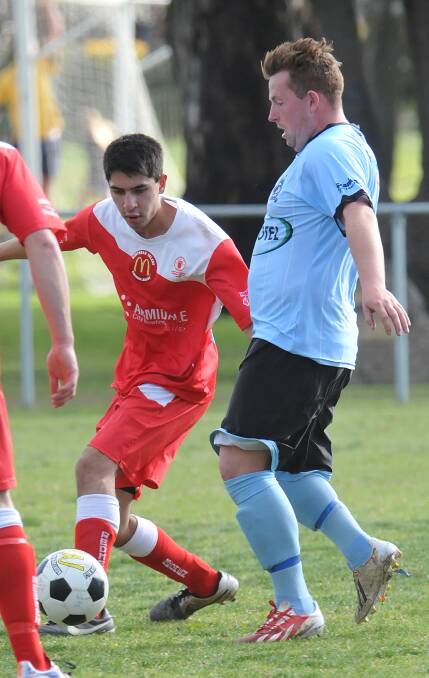 North Armidale’s Anil Rajanathan (left) will be a loss for the Redmen when they tackle OVA this Saturday. Here Rajanathan slips in against Tamworth FC’s Michael Roberts.  Photo: Geoff O’Neill 060914GOF04