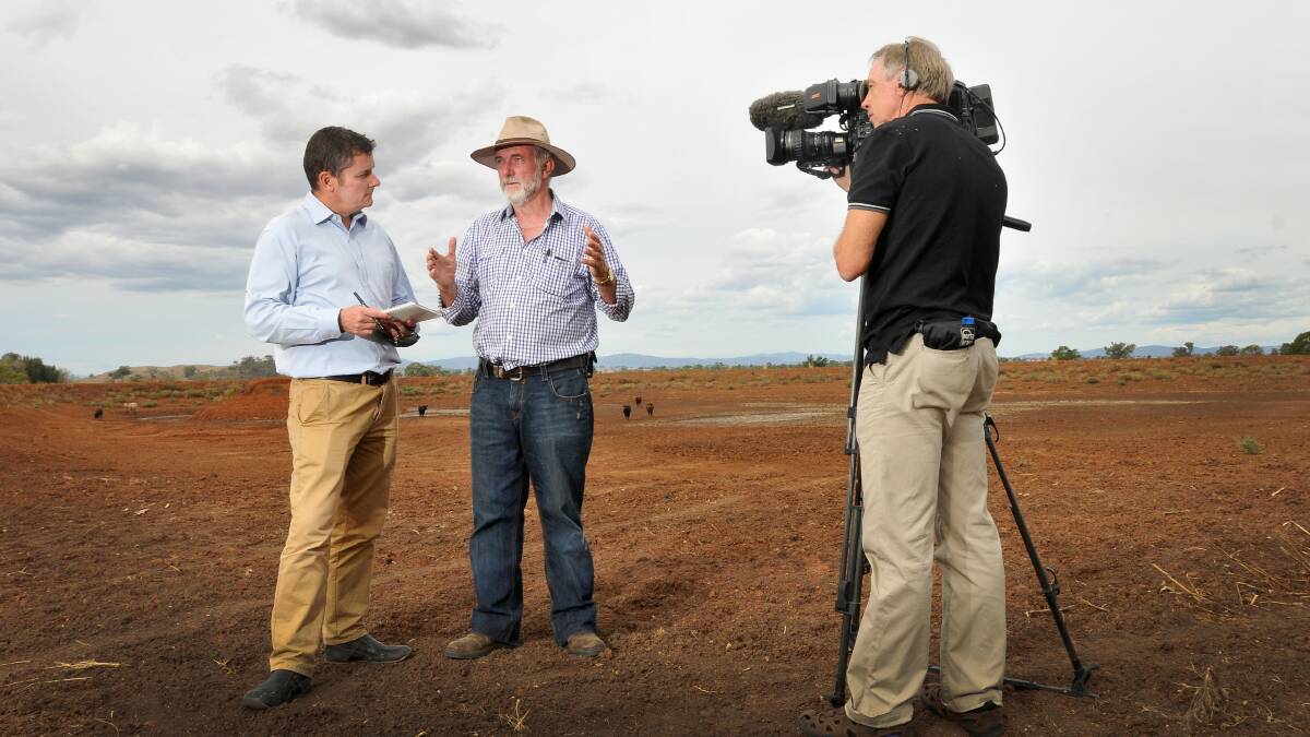 INTERNATIONAL ATTENTION: A BBC production crew interviews Russell Webb on the drought while standing at the base of an empty dam on his property. Photo: Gareth Gardner 260214GGF01