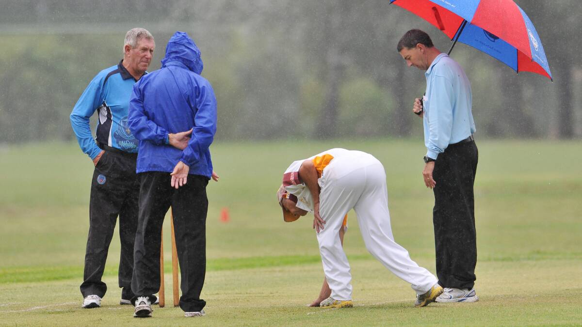 City captain Peter Mead inspects the wet Riverside 2 wicket whilst three TDCA officials discuss the chances of the game continuing on Saturday.  
Photo: Gareth Gardner 290214GGE01