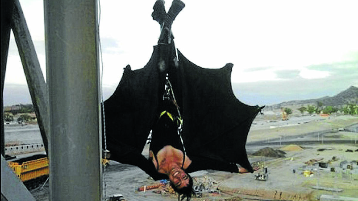 HOLY INTERRUPTIONS: An anti-coal protester dressed in a bat costume hangs upside down from a coal loader at Idemitsu’s Boggabri mine. 