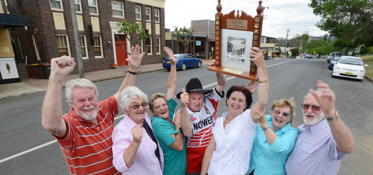 GOING FOR GOLD: Nundle residents, from left, Robert Schofield, Marcia Schofield, Maureen Smith, Billy Smith, Kay Burnes and Anne and Geoff Cummins celebrate the town’s NSW win in November last year. On Friday they’ll battle it out for the national honour. Photo: Barry Smith 031113BSF07