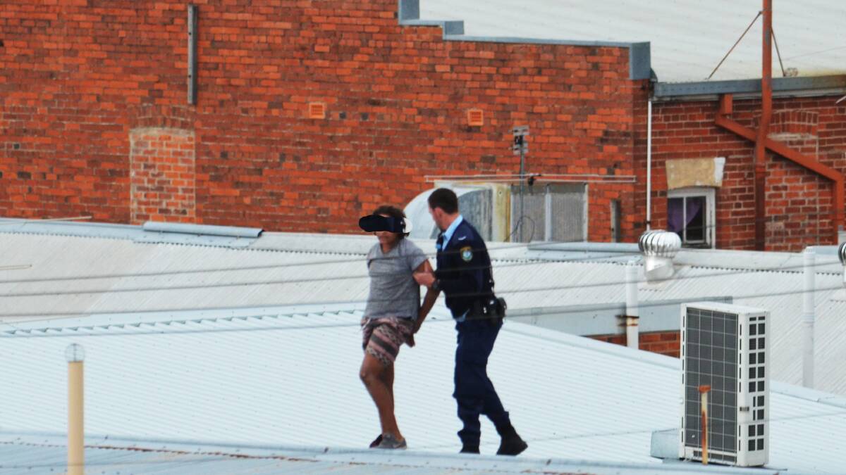 REFUSED BAIL: The teenager is led off the roof by police after he was arrested on Sunday afternoon. Photo: Chris Bath 170814CBB05