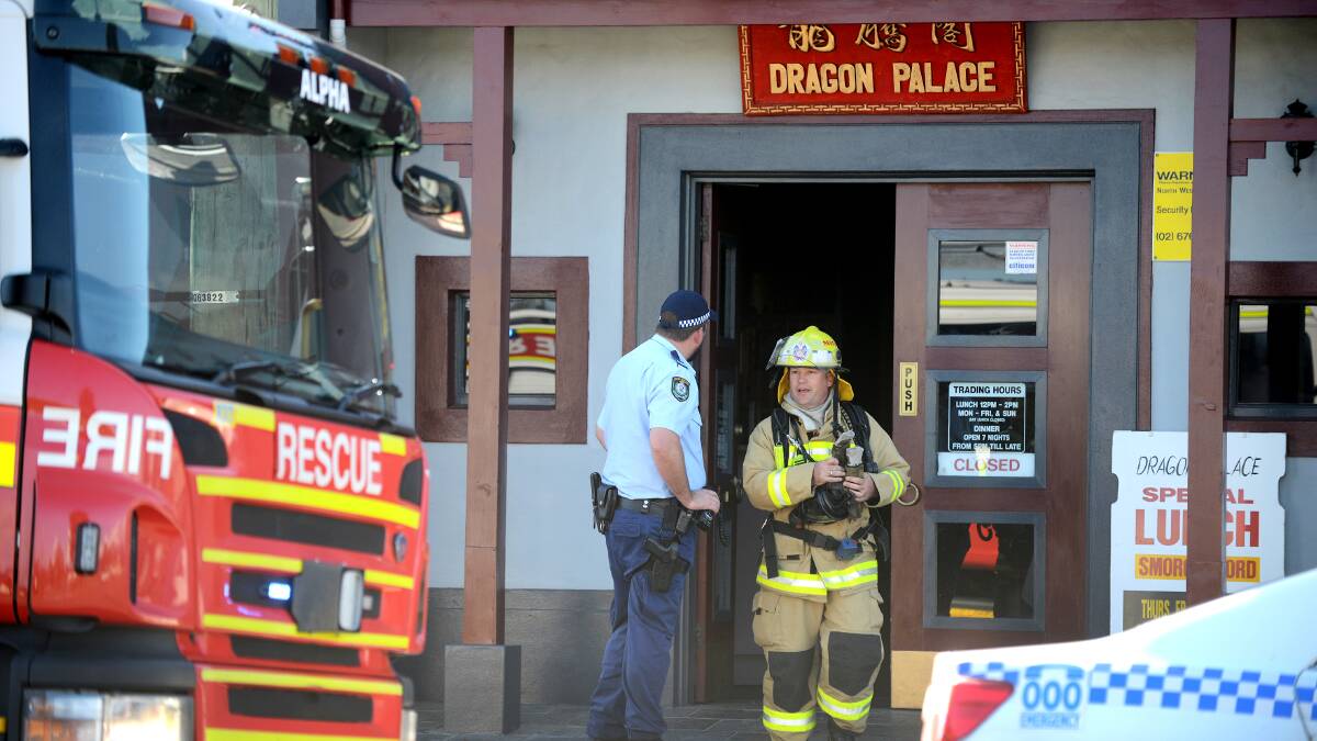 MINOR DAMAGE: A Tamworth firefighter emerges from Dragon Palace Chinese Restuarant and speaks to a police officer after a kitchen fire. Photo: Barry Smith 220614BSB04