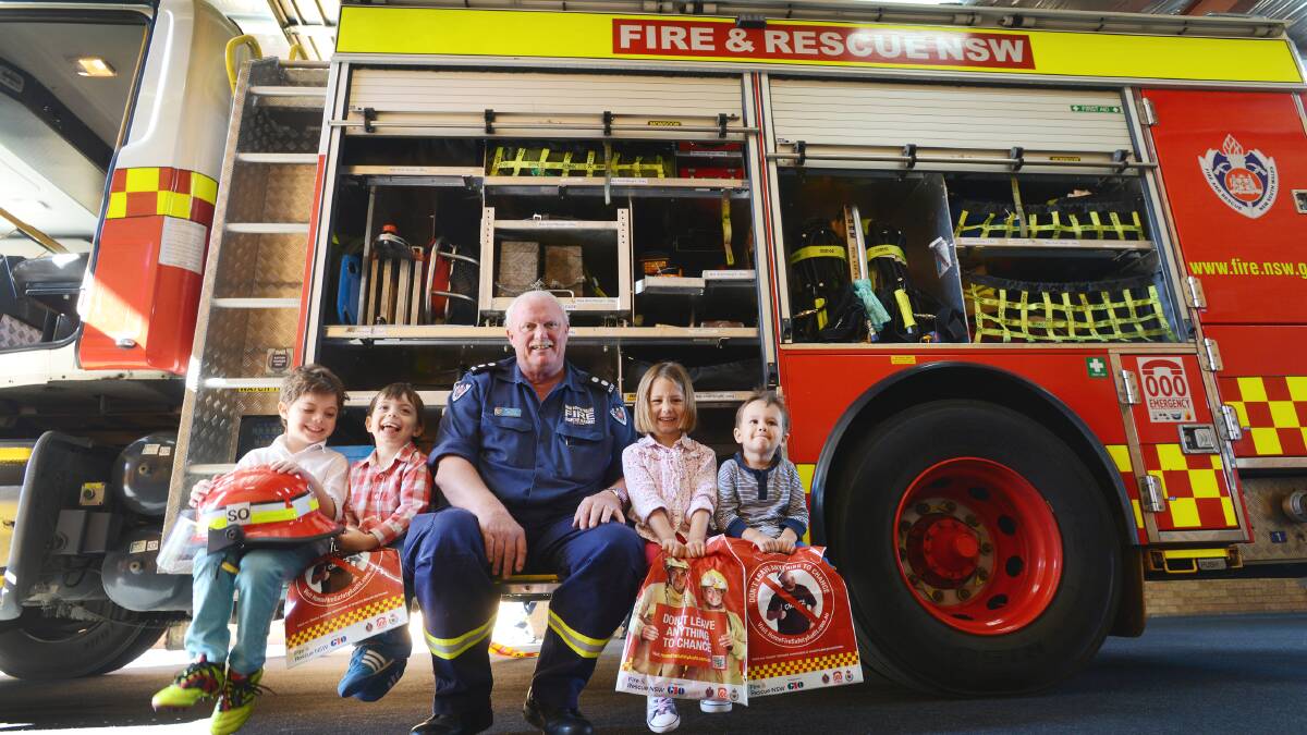 LEFT – TALKING SAFETY: Tamworth Fire Station Officer Bob Luck, pictured, was one of dozens of firefighters across the region spreading the fire safety message to families including, from left, Mac and James Lesslie and Cleo and Jude Graystone. Photo: Barry Smith 170514BSA03