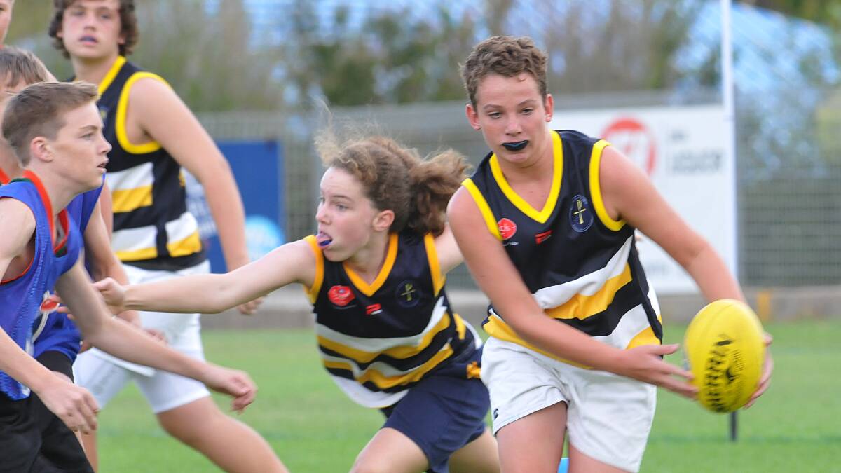 Farrer's Peter Williams (left) tries to stop McCarthy's Will Clinch during their clash on Friday night. Also in view are Adam Wallace (background) and Elle George. 140314GOE02