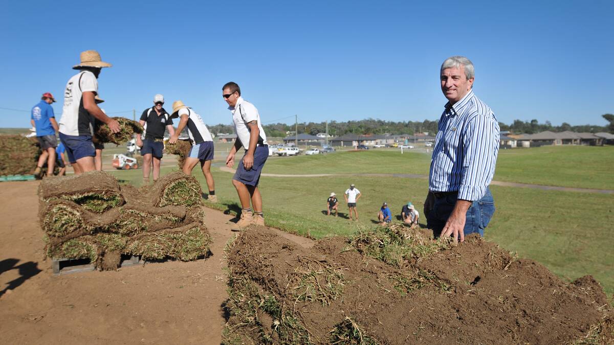 LEAN AND GREEN: Single Builders director Mark Single, right, oversees the laying of turf at the Redbank Estate subdivision. The $400,000 park will be one of the most impressive in the city. Photo: Geoff O'Neill 240414GOA01