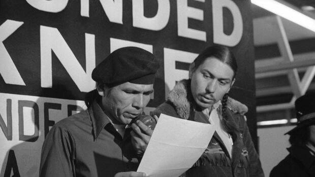 Banks, left, reads an offer by the US government seeking to effect an end to the Native American takeover of Wounded Knee. Photo: AP
