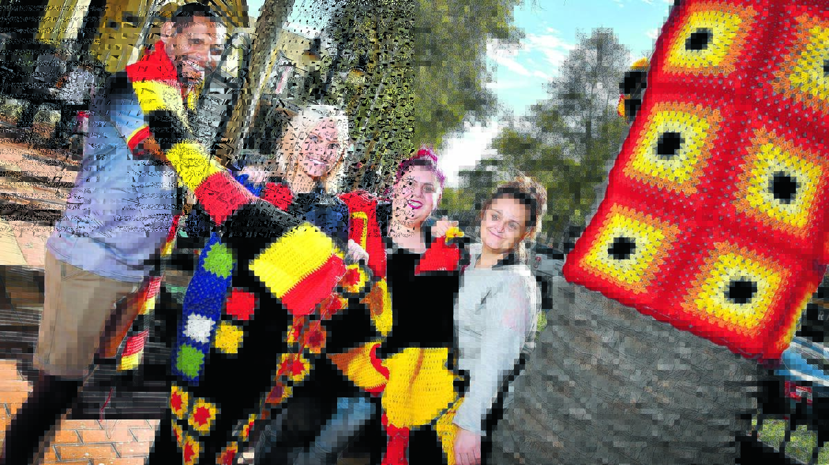 WARM AND COSY: Yarn bomber supporters, from left,  Patrick Strong, Sam Ruttley, Kristle Nicol and Lakeisha Hile helped dress up the palm trees in Peel St in winter woolies for the Indigenous celebrations next week. Photo: Barry Smith  300616BSB01