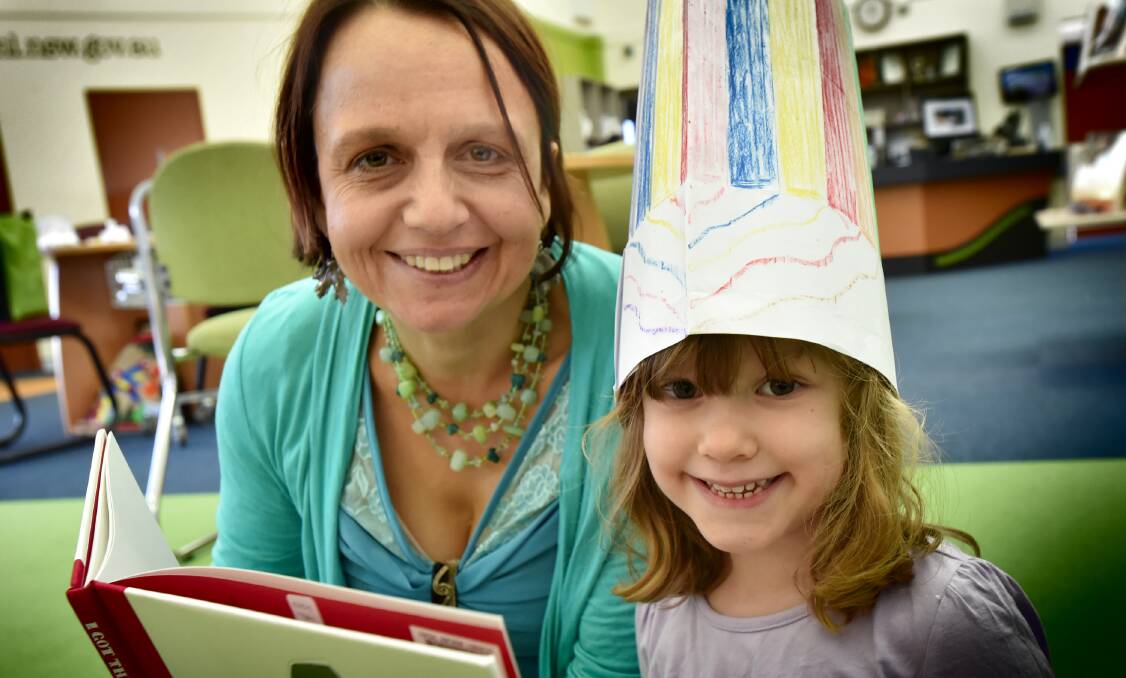 SHARED STORIES: Library assistant Jacqueline Smith and Maeve Graham, 4, settle in for the national storytime. Photo: Geoff O’Neill 250516GOA01