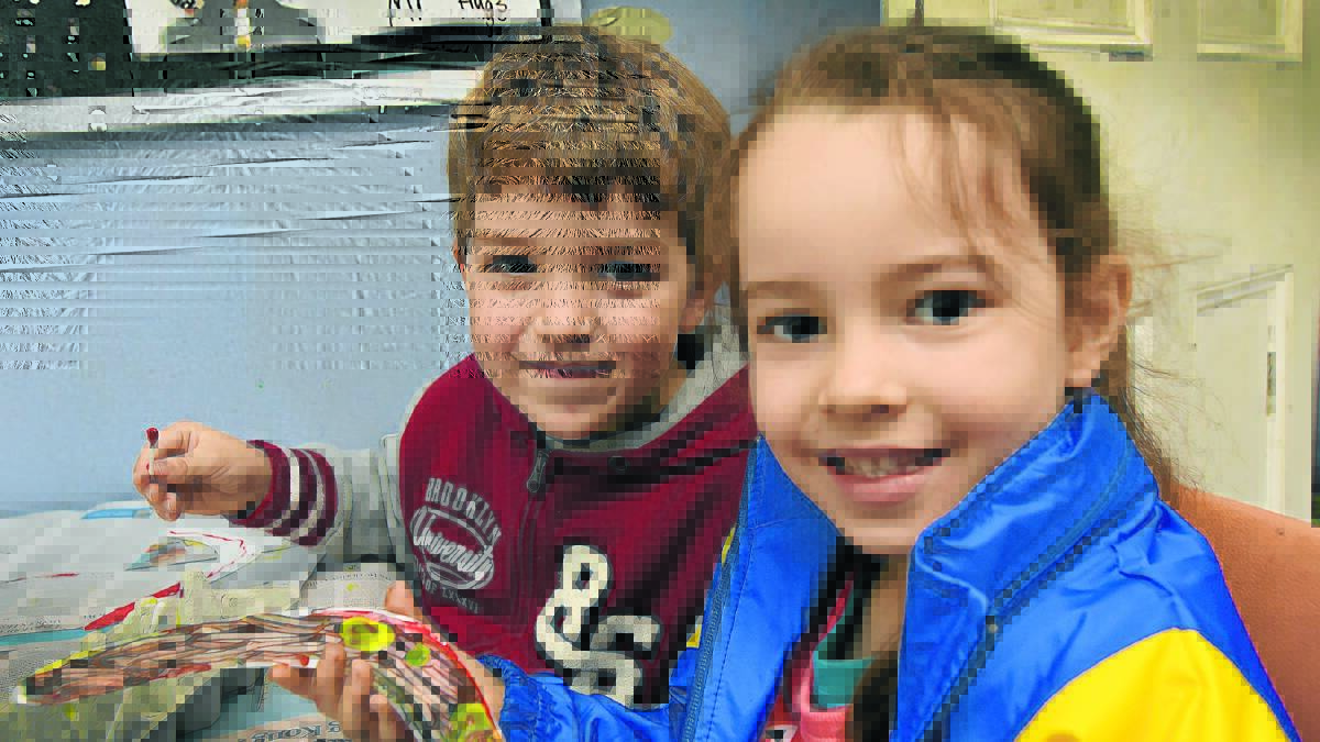 ALL SMILES: Riley Clibborn and Sophie Celovic, both 5, trying their hand at boomerang making as part of the holiday care program at TPS. Photos: Geoff O’Neill 050716GOA04