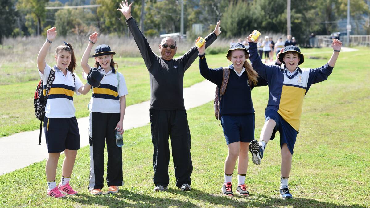 WALKING TALL: Parish priest for St Nicholas Primary, Father Joe Adriano, with McCarthy students, from left, Chelsie Shaw, Madison Kelly, Mary Howard and Bailey McNamara get fired up for a day of raising funds. Photo: Geoff O'Neill 280815GOD01
