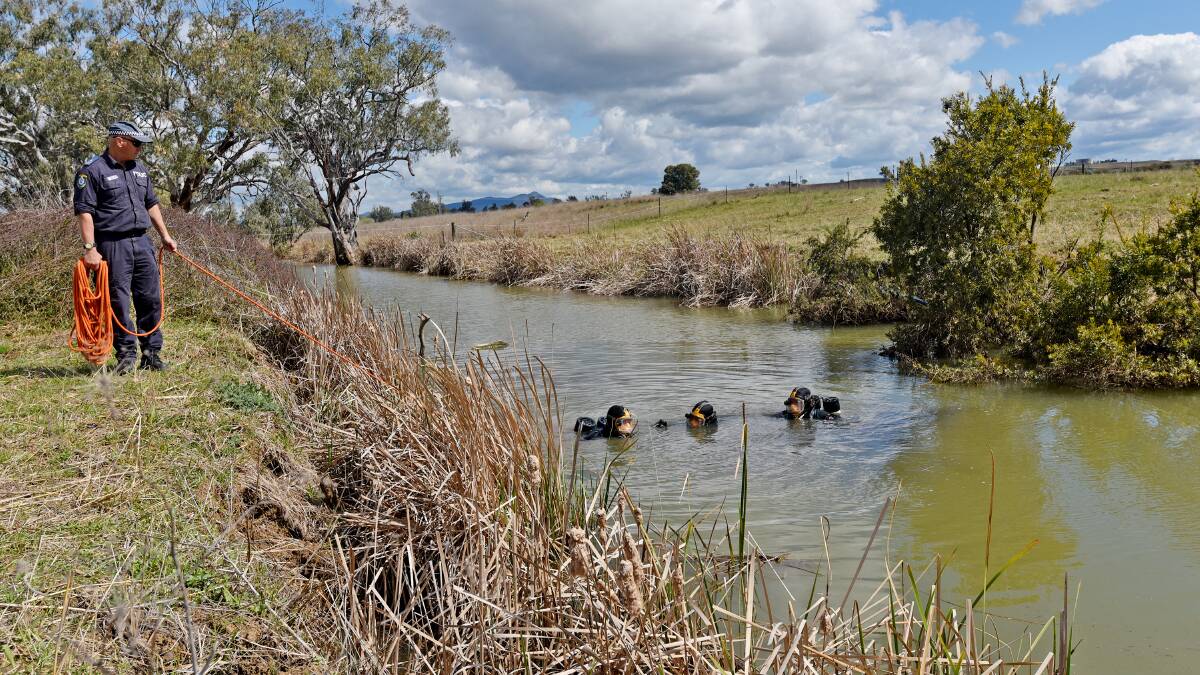 SEARCH FOR CLUES: Police divers scour Timbumburi Creek yesterday. Photo: Geoff O’Neill 280815GOF02