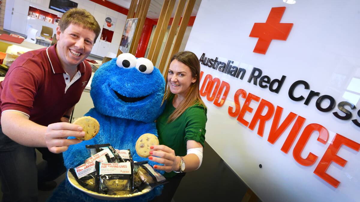 CRUMB ON DOWN: Blood donor James Harrison and Alanna Garn from the Australian Red Cross Blood Service with the Cookie Monster rating the biscuits as the best in Australia and worth a donation to get your teeth into one. Photo: Barry Smith 080915BSB02