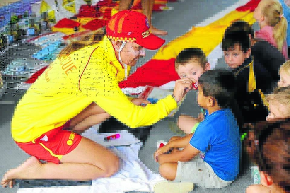 SURF AWARENESS: Angie Thorpe from South Narrabeen Surf Lifesaving Club applies some zinc to a St Michael’s primary school student after he correctly answered a question.