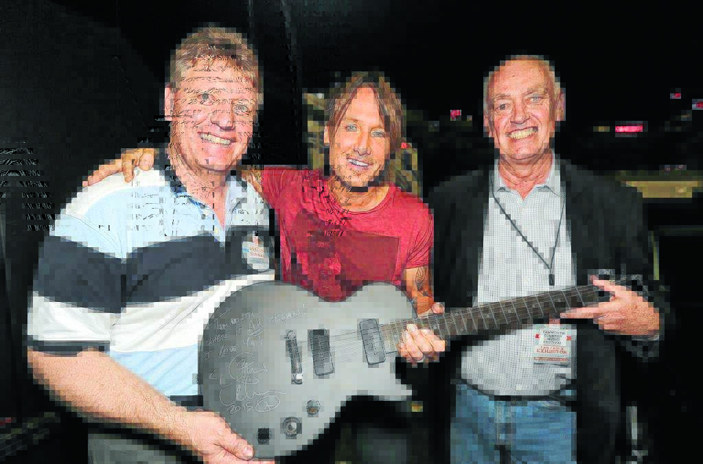 URBAN BOOST: Keith Urban, centre, presents his signed guitar to Tamworth festival executives John Sommerlad, left, and Barry Harley in Nashville during the council delegation visit.