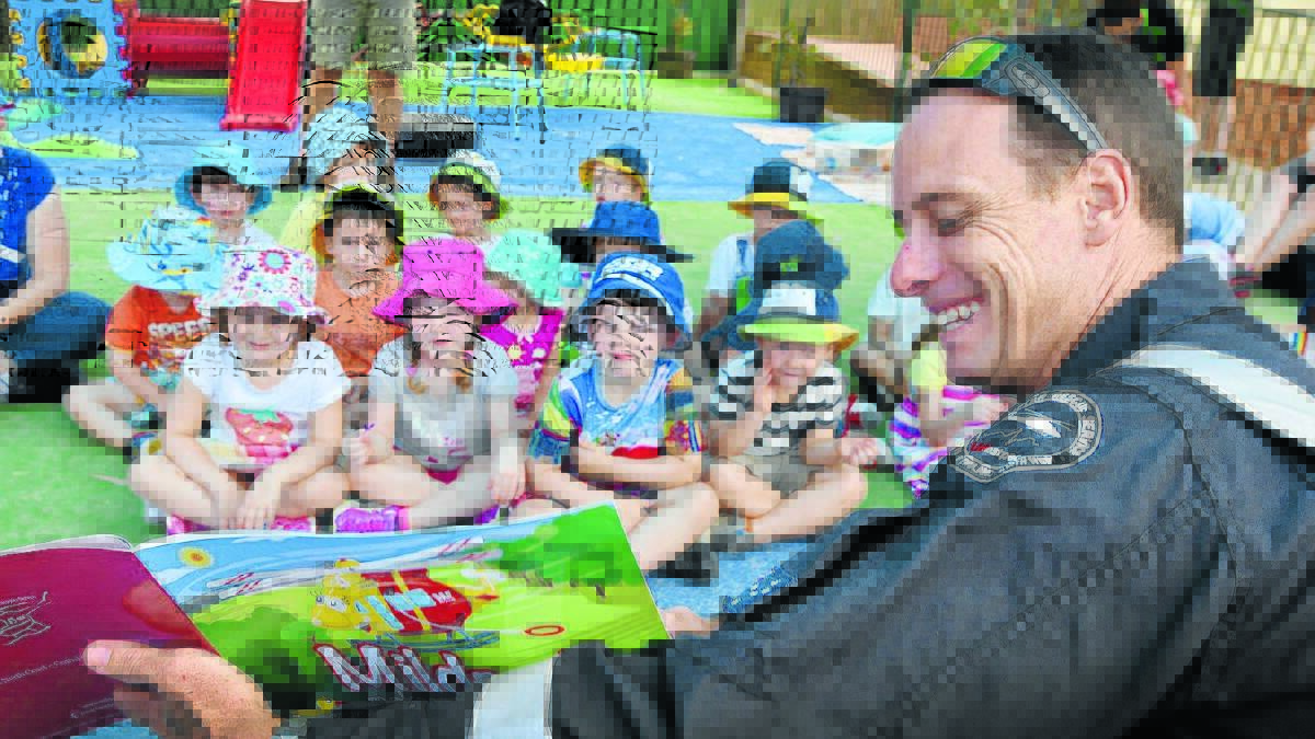 LISTEN UP: Westpac Rescue Helicopter Service crewman Sean Maher reads to the children at Tamworth’s Nurture One. Photo: Geoff O’Neill 040216GOA02