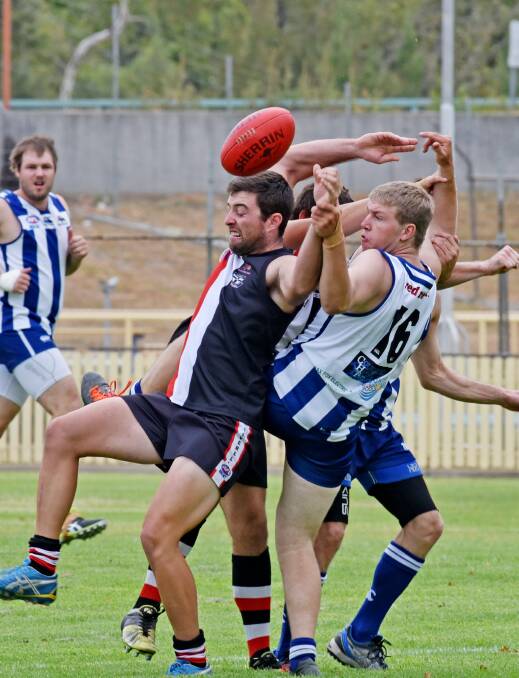 Saints’ Anthony Pages (left) and Tamworth Kangaroo Todd Brazel are part of a four-man scrimmage at No 1 Oval on Saturday. Pages kicked one of the 11 goals for his side in their 13-point win. Photo: Geoff O’Neill 090416GOB05