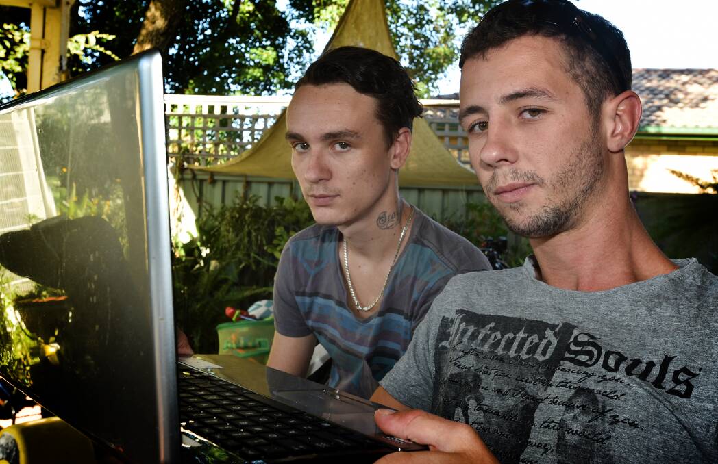 HATE-FILLED POSTS: Dean Ross (right) and friend Steven Gillies (left) scroll through the dozens of malicious messages, including death threats and homosexual slurs, posted on Facebook against them in recent days. Photo: Geoff O’Neill 160315GOF01