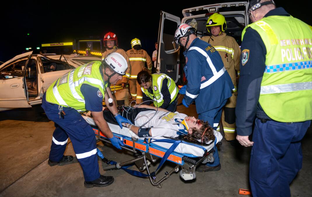 ROLE PLAY: Paramedics transport the patient from the crash scenario into the waiting ambulance. 230816PHA45