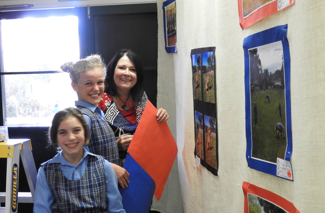 ART SHOW: Sienna Marzato and Phebe McNamara with principal Leisa McMahon from Woolomin School prepare their display.