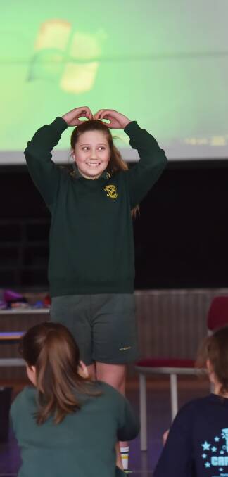 HANDS ON HEADS: Mataya Gabutto from St Nicholas' Catholic Primary School stands tall in front of the crowd of students. 180816GGB04