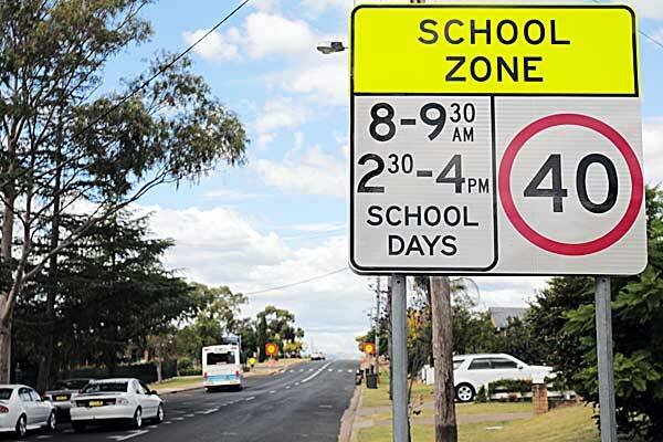 NO LIGHTS HERE: The school zone sign outside St Edward’s Primary School on Hillvue Rd, while 400 metres further along the street the Hillvue Public School signs have been fitted with flashing lights. Photos: Robert Chappel 280312RCI04