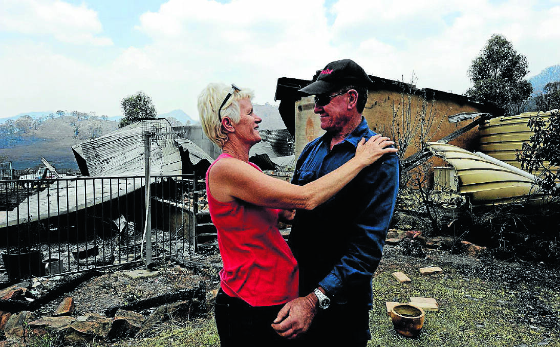 HOme: Dawn Keirle hugs her neighbour Perry Wilkinson in front of her Timor Rd property which was destroyed by the Coonabarabran fire last January. A year on, the tight-knit community remains in the rebuilding phase.