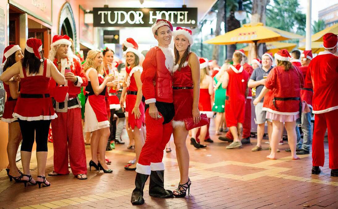 CHRISTMAS CRAWL: Santa Crawl organiser Chris Watson, pictured with wife Gemma and a number of Santas, said the event had boomed in the past three years thanks to social media.  Photo: Nita Bread Photography