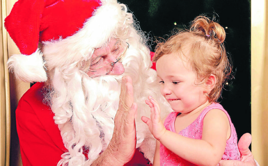 HEALING HANDS: Santa’s helper at City Plaza, Brian Stocks, connects with two-year-old Sienna Morgan this week. Mr Stocks says the position is a richly rewarding one. Photo: Robert Chappel Photography