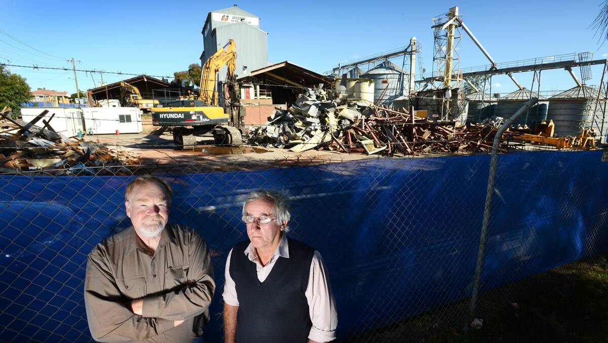 WHAT PRICE PROGRESS?: Outraged residents David Saunders and Bill Bryan at the demolition site of the old Weston Animal Nutrition factory, which is likely to pave the way for a new Woolworths supermarket and Dan Murphy’s bottle shop. The proposed development has met stiff opposition from police, hoteliers and residents. Photo: Barry Smith 230913BSD08 