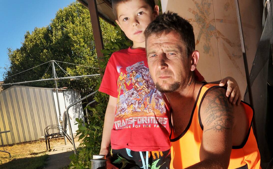 FED UP: Tamworth dad Ben Hudson, pictured with son Matty, 7, arms himself with a metal bar when going into his backyard, due to concerns his neighbour’s pig-hunting dogs could attack his children. 290114GGA03