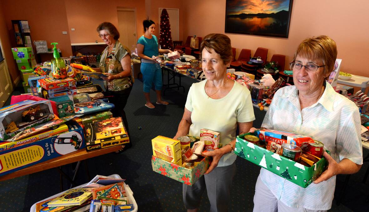 HELPING HAND: Uniting Church volunteers, from left, Judy Carthew, Kadie McGuiness, Betty Johnston and  Lorraine Furze pack up food and gift hampers for the needy this Christmas. Photo: Barry Smith 181213BSF01