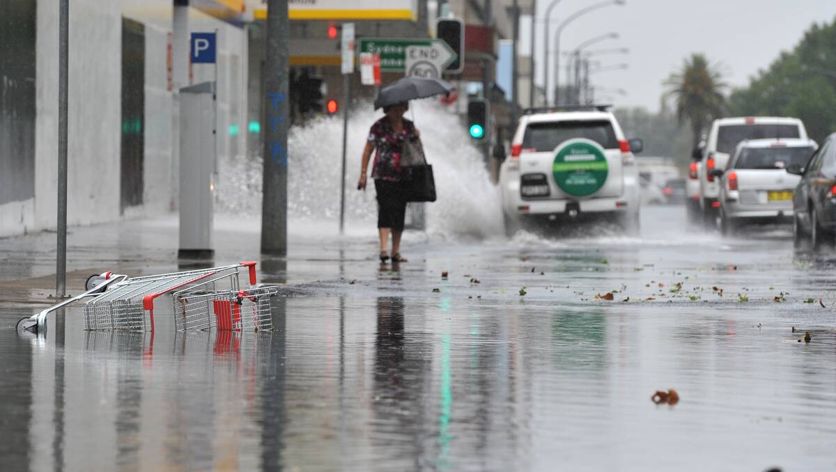 A woman walks along Kable Ave as storm waters rise. Photo: Barry Smith