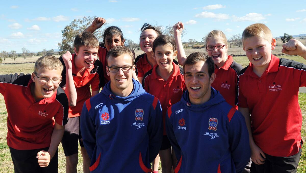 left –  FOOTBALL FEVER:  Newcastle Jets Jack Duncan and Ben Kantarovski  visited students at Carinya  Christian School yesterday  afternoon.   From left, Samuel Learson, Thomas Murphy, Nineesha Veer, Melodee Mooy, Mikaela  Raeburn, Madeleine Henry and Tobias Maslen were pleased to see them.  Photo:  Geoff O’Neill 310812GOE01