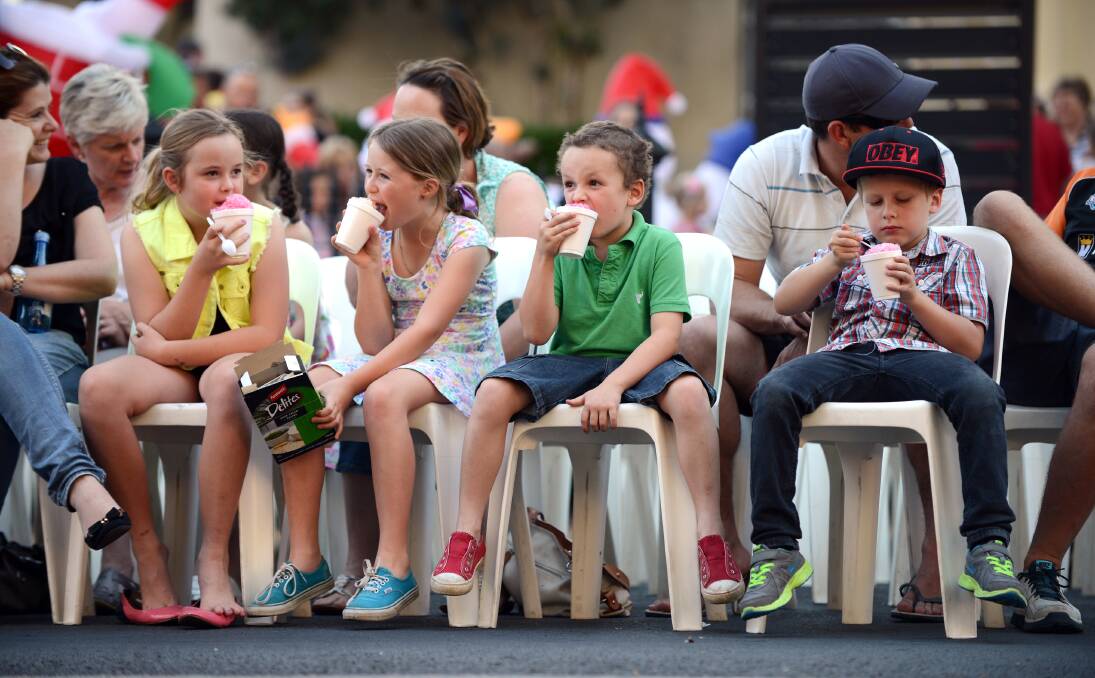 COUNTDOWN: From left, Charlotte Henderson, 8, Bianca Roper, 9, Jacob Henderson, 6, and Ashton Roper, 7, munch on snow cones as they wait for the Christmas tree light ceremony to begin. 021213BSH12