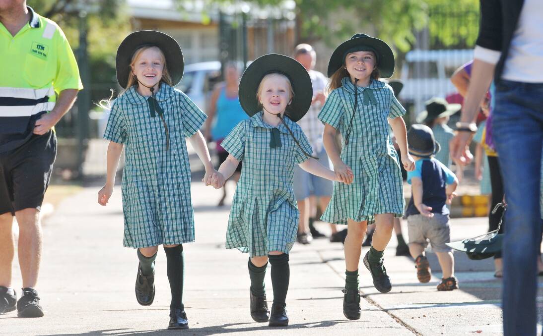 CHEERFUL: Tamworth Public School’s Mia and Anna Pollard and Lara Chappell skip into school. 290114GGB08