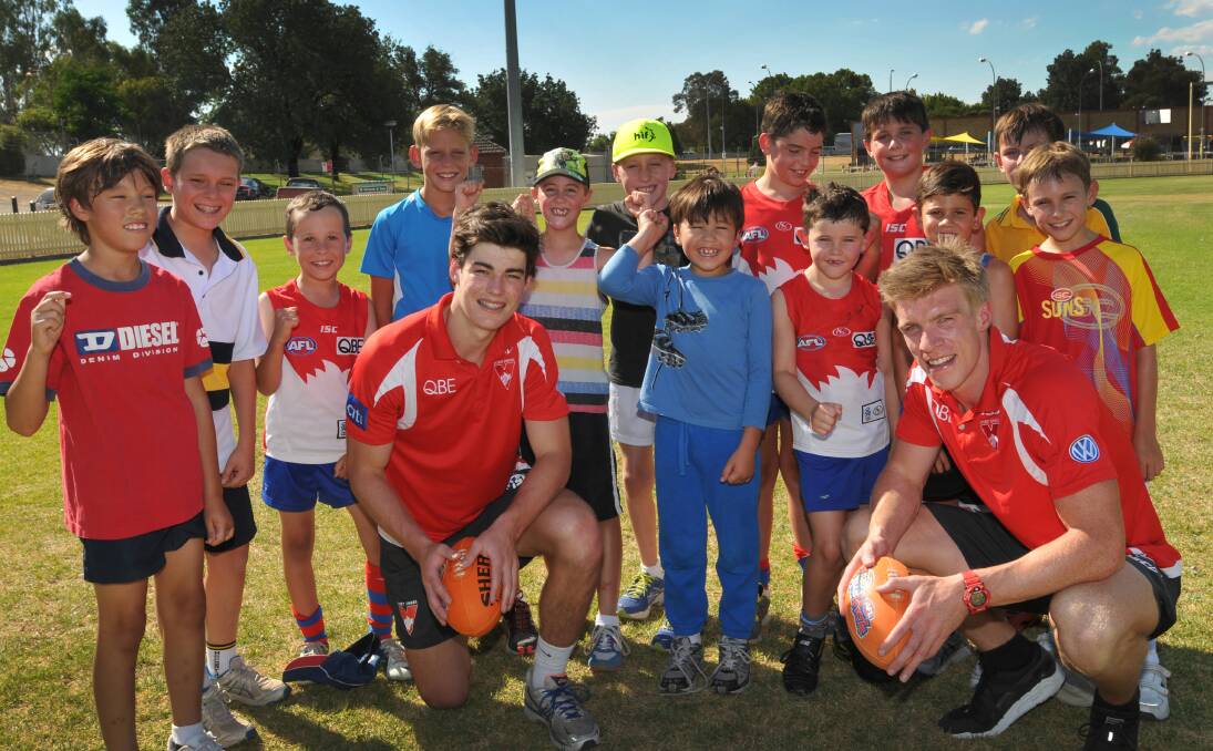 Sydney Swans George Hewett (front left) and Tommy Walsh (right) had a run around with some young AFL enthusiasts  yesterday. Photo: Geoff O’Neill 100214GOD01