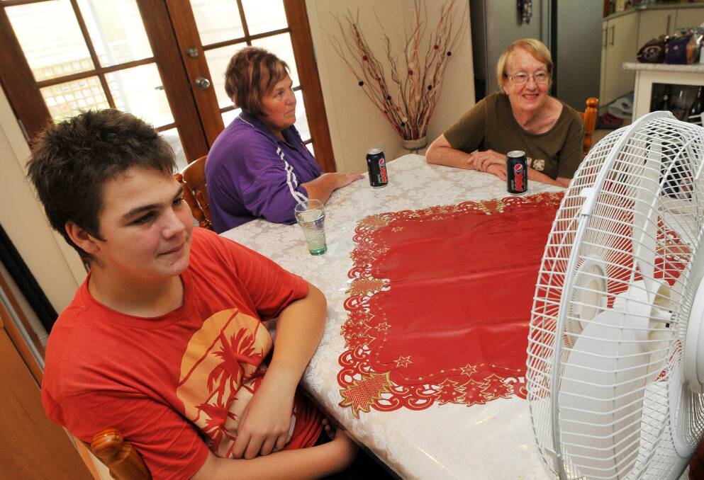STAY COOL: Matthew Holz, 13, his mum Terrie Holz and grandmother Leila Holz huddle around a fan to cool off yesterday. Many local families are struggling this summer with the rising cost of electricity. Photo: Gareth Gardner 030114GGD01