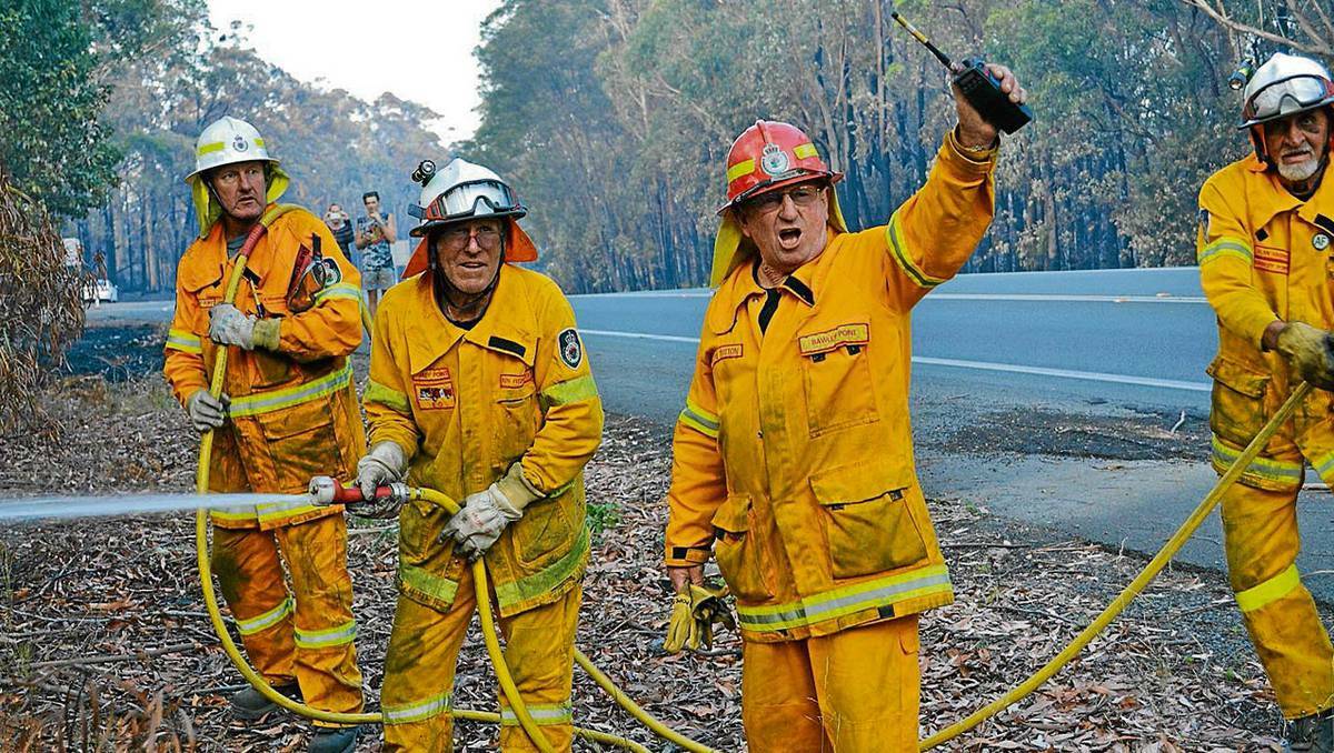 EMERGENCY: As flames erupt beside the Princes Highway south of Nowra on Wednesday evening, Bawley Point Rural Fire Brigade members Charlie Magnuson, Ken Fitzpatrick, captain Lloyd Tutton and Alan Harris grab their hoses and prepare to rush towards the flames.