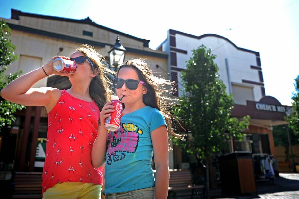 Melbourne visitors Teagan Denny, 12, and Brianna Denny, 10, cool off with a drink in the breeze at Maitland this morning. Pic: MARINA NEIL
