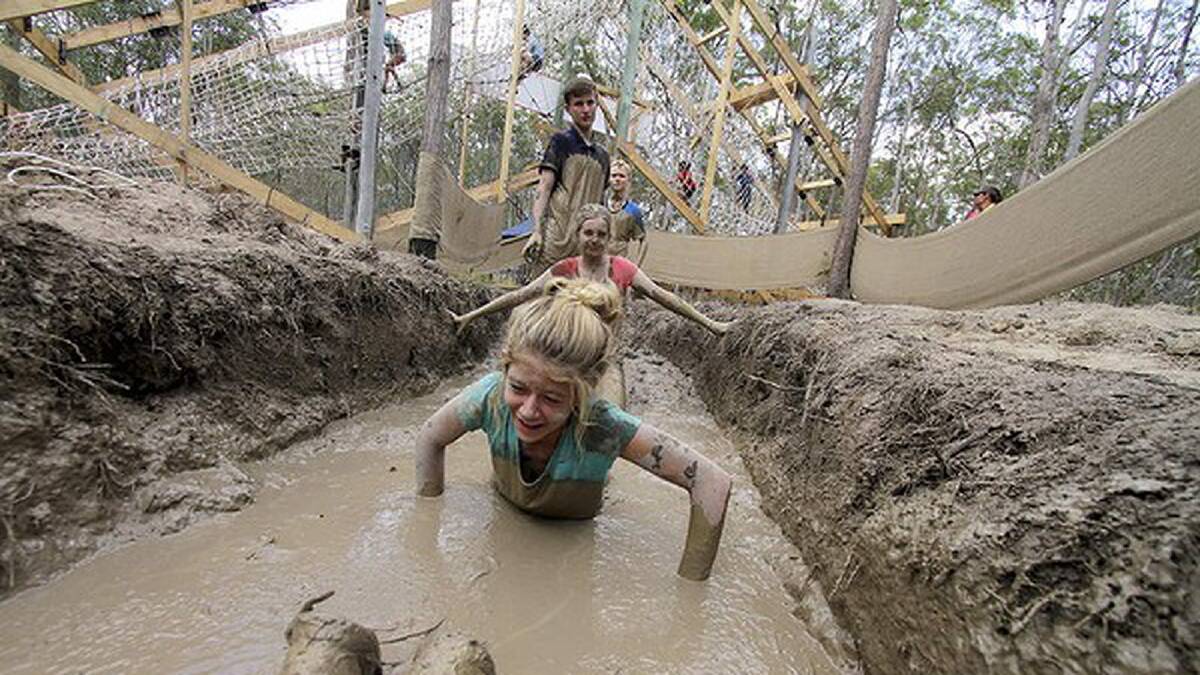 Meg Wilhelmi, 13,(front) and Hayley Hobson, 13, both from Alice River, Townsville, QLD, go through the mud obstacle course. Photo: Michelle Smith