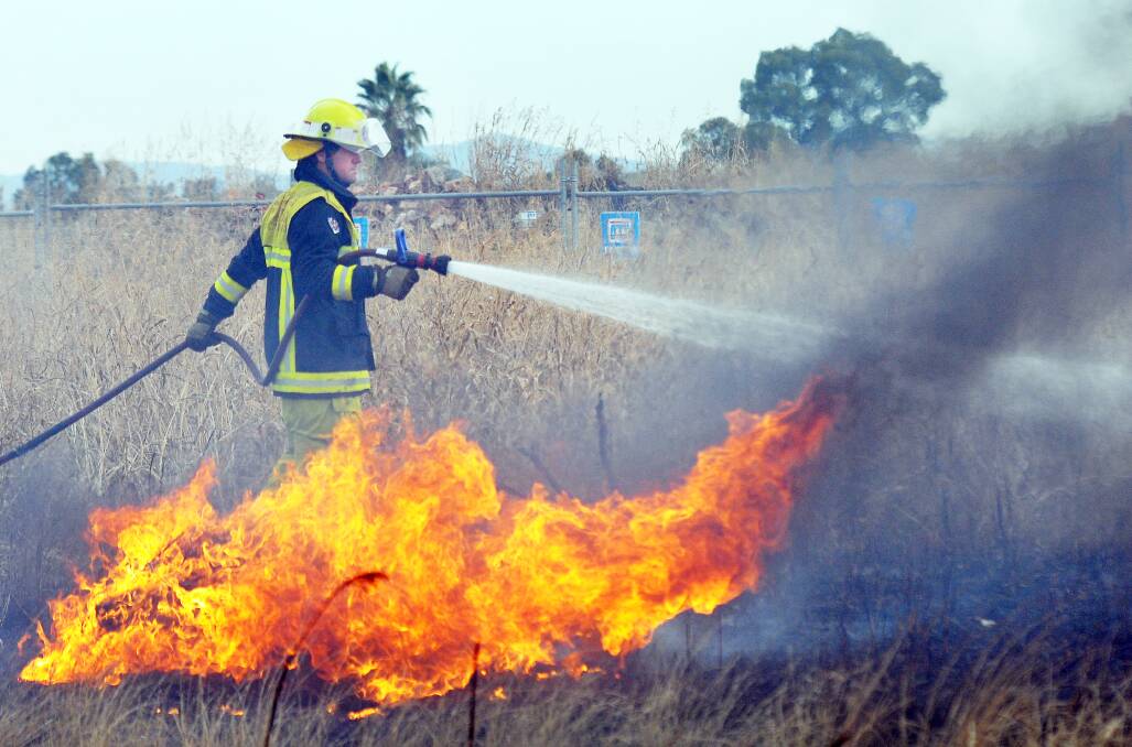 Firefighters work to put out a grassfire in Tamworth in May. Photo:Geoff O'Neill 020513GOH01