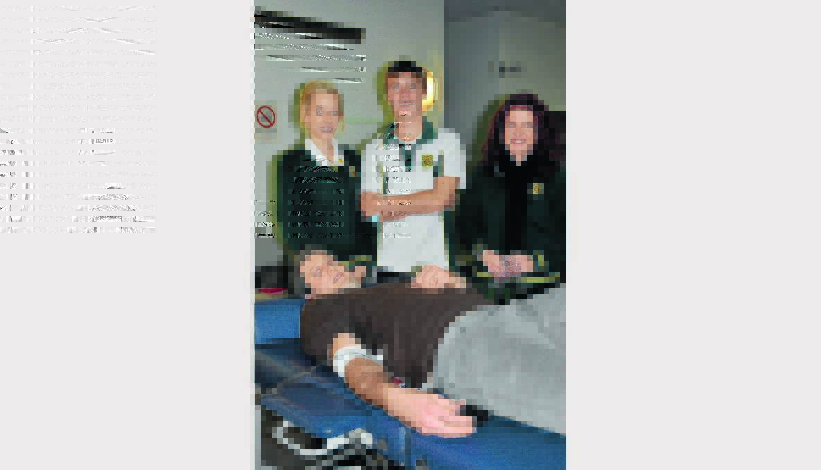Gunnedah High School Year 11 students, Sophie Hendrie, Kih McDonald and Kayla Smith watch on as teacher Benji Trieger donates blood last week. Gunnedah High is a regular visitor to the mobile blood clinic and promotes other school groups/organisations to do the same. Photo: Ashley Gardner, Namoi Valley Independent. 