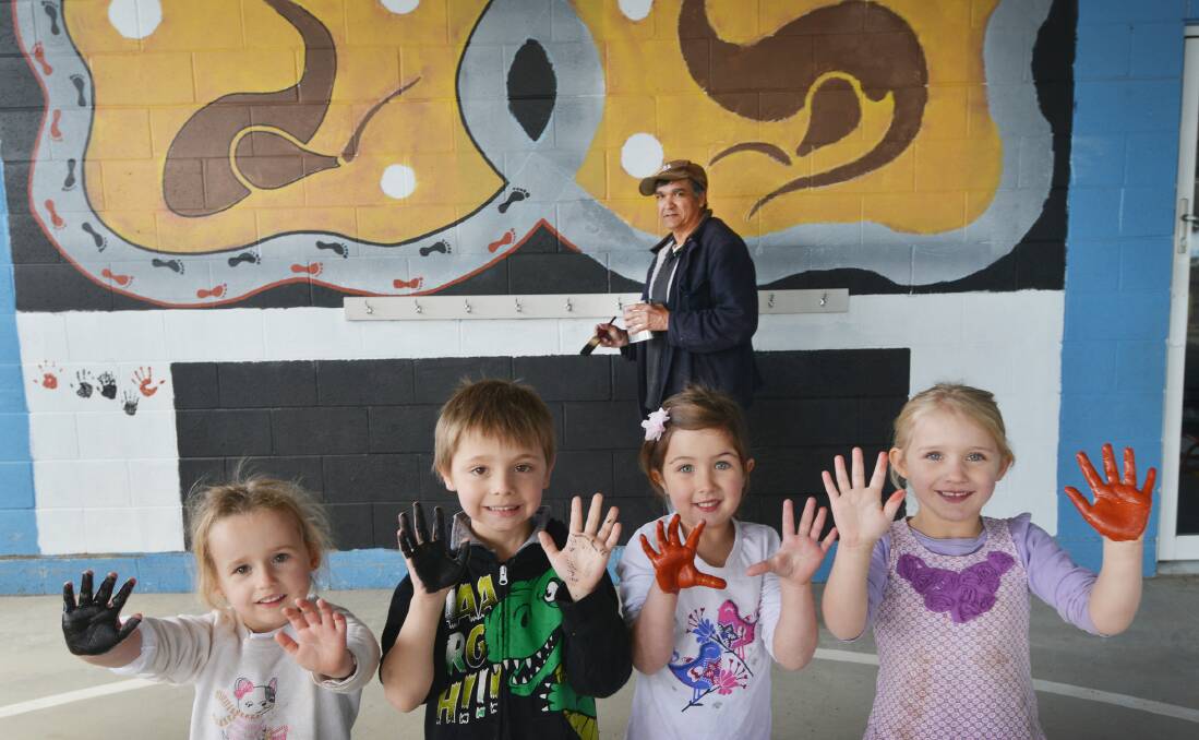 HANDY WORK: Sieshia Mood (4), Ben Kingham (5), Eliza Buckley (5) and Callie Jarrett (4) have added their prints to a painting by Aboriginal artist Anthony Conlan. Photo: Barry Smith 050815BSE02