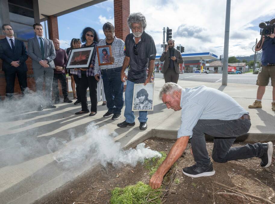 Family of Mark Anthony Haines hold photographs of the Gomeroi teenager during a smoking ceremony outside the Tamworth Court House. Picture by Peter Hardin
